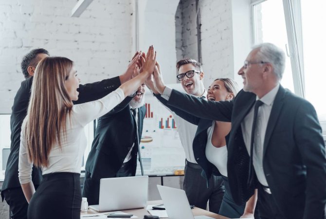 cheerful-business-team-giving-each-other-high-five-to-success-while-working-in-the-modern-office.jpg