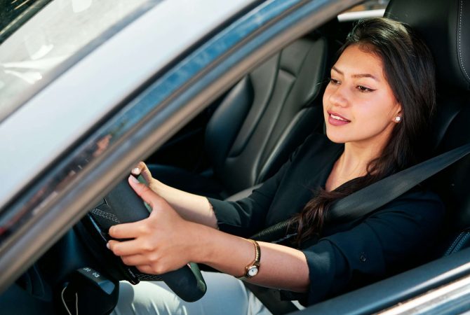 young latin woman driving luxury car